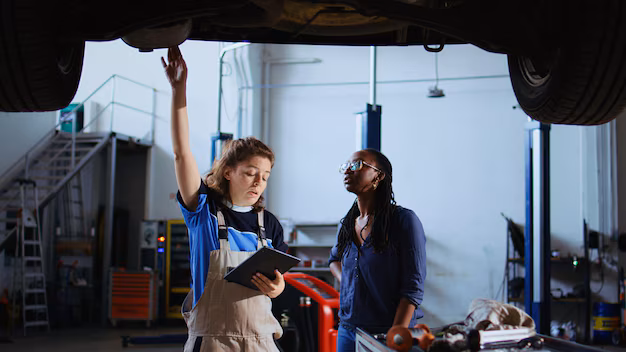 mechanic-customer-standing-underneath-car-garage-using-laptop-order-new-parts-after-finding-fire-hazards-expert-assisting-client-by-looking-components-online-zoom-out-shot